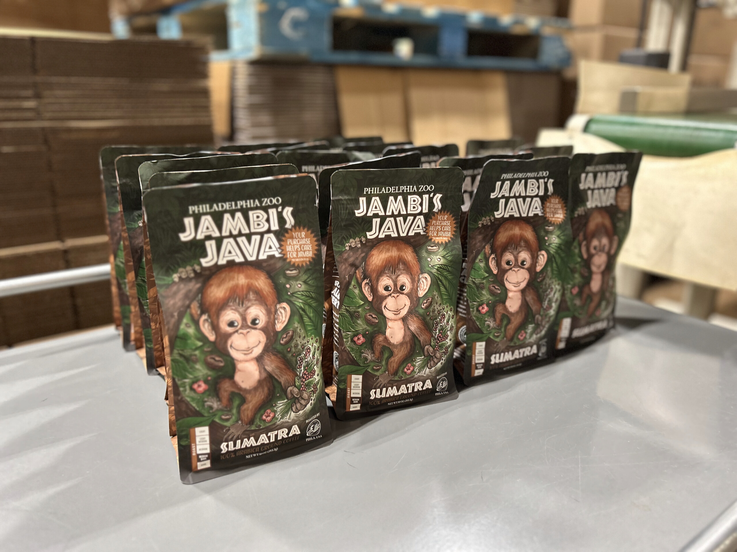 Several bags of Jambi's Java coffee sit on a table. The bag features a hand-drawn illustration of Jambi, the baby orangutan recently born at Philadelphia Zoo.